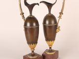 pair of antique brass and marble vases on stands on a white background