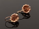 a pair of rose earrings on a black surface