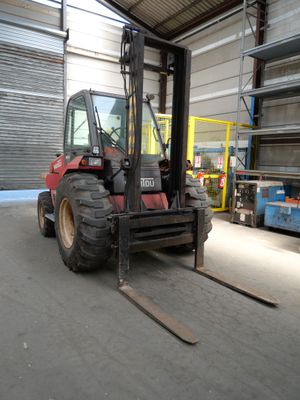 un chariot élévateur garé dans un entrepôt, avec des palettes en arrière-plan