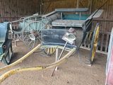 une calèche dans une grange, à laquelle est raccordé un tuyau d'arrosage
