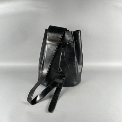 Le petit sac seau noir est posé sur une surface blanche.