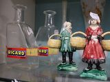 trois figurines représentant des femmes tenant des paniers, posées sur une étagère