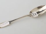 silver spoon with writing on it sitting on a white surface