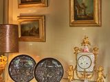 une table avec une horloge, une lampe et des tableaux accrochés au mur