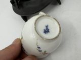 a person holding a small white vase with a blue flower on it