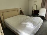 a bed with white sheets and pillows in a bedroom