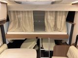 a small bed in the back of a camper with a couch underneath it