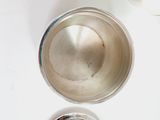 a silver cup sitting on top of a table next to a bottle