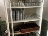 un placard sur lequel sont posés de nombreux verres, dans la cuisine