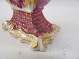 a purple and gold vase on a white table