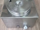 a silver stove with two pans on it on a wooden floor