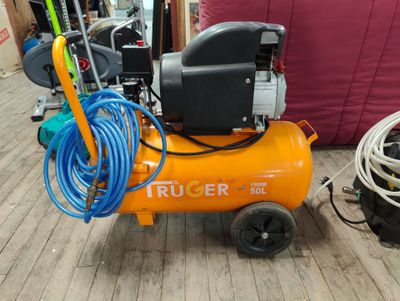 un petit compresseur d'air orange posé sur un plancher en bois
