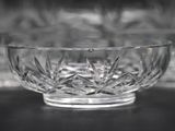 a glass bowl sitting on a table in front of a shelf