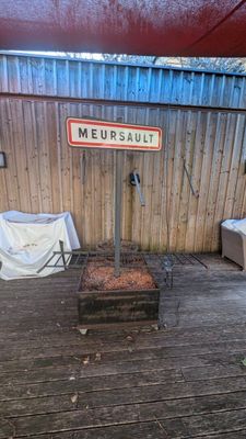 un barbecue posé sur une terrasse en bois, avec une pancarte dessus
