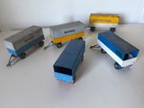 Plusieurs camions miniatures sont alignés sur une surface blanche