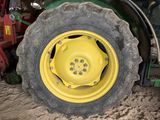 a yellow wheel of a tractor that is parked in the dirt