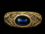 gros plan d'une bague en or avec une pierre bleue