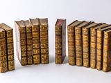 several old books are lined up in a row on a white surface