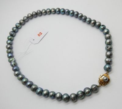 un gros plan d'un collier muni d'un fermoir doré, posé sur une surface blanche