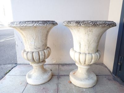 two white vases sitting on the sidewalk next to each other