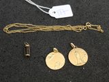 un gros plan d'un collier en or orné de deux pendentifs, posé sur une surface noire