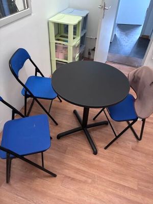 une table noire entourée de quatre chaises bleues