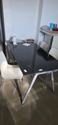 a black table with white chairs and a laptop on it