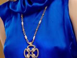 La femme porte une robe bleue et un collier en or.
