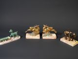 three bronze figurines of horses and a man on a horse drawn carriage