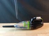 un petit aspirateur noir et vert posé sur une table en bois