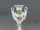 un vase blanc orné d'un motif floral, posé sur un socle