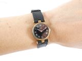 wrist shot of a woman wearing a black and gold watch