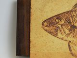 painting of a fish on a piece of wood on a white surface