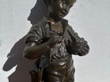 bronze statue of a boy holding a bird on a wooden base