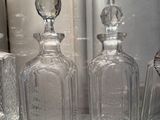 three glass bottles sitting on top of a glass shelf