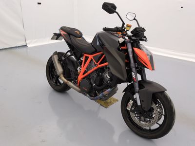 une moto noire et orange garée dans une pièce blanche