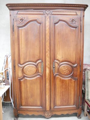 une grande armoire en bois dans une pièce où se trouvent de nombreux meubles