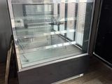 an empty glass display case in the corner of a room