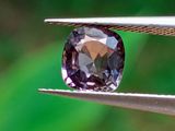 quelqu'un tient une pince dans laquelle est sertie un diamant violet