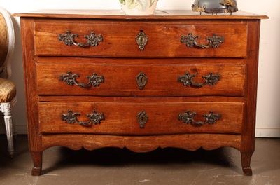 une commode en bois sur laquelle est posé un vase de fleurs