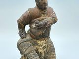 une vieille figurine représentant un homme assis sur un rocher, tenant un poisson