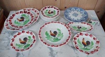 de nombreuses assiettes et bols décorés de coqs, posés sur une table