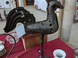 une statue de coq posée sur une table sur laquelle se trouvent des vases