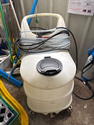 un réservoir blanc auquel est raccordé un tuyau, dans un garage