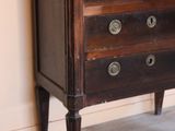 a small wooden chest of drawers in the corner of a room