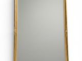 a gold framed mirror on a white wall with a white background
