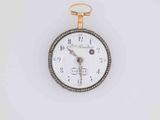 a gold and silver pocket watch on a white surface