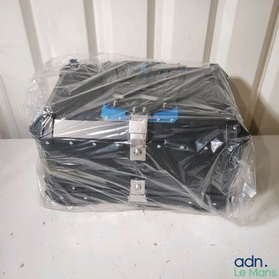 a black suitcase wrapped in plastic on a white table