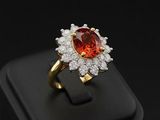 a gold ring with a large red stone surrounded by white diamonds