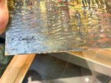 someone is holding a painting in their hand in front of a glass case